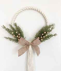 a tasselled wreath with pine cones and berries tied to the front, hanging on a white wall