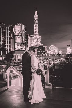 a bride and groom pose for a photo in front of the eiffel tower