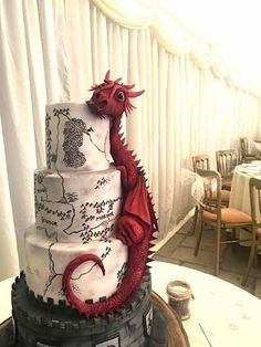 a three tiered cake with a red dragon on it's side sitting on top of a table