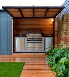 an outdoor kitchen is built into the side of a brick building with grass in front