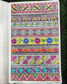 an open notebook with colorful designs on the pages and green grass in the foreground