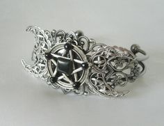 This beautiful silver plated filigree cuff bracelet has a silver plated triple moon design and a pewter silver pentacle with obsidian settings. Adjustable. Adjustable Silver Gothic Jewelry, Adjustable Gothic Silver Jewelry, Gothic Silver Jewelry For Festival, Gothic Silver Festival Jewelry, Gothic Adjustable Bracelet, Adjustable Gothic Bracelet, Adjustable Mystical Silver Bracelet, Adjustable Silver Mystical Bracelet, Gothic Silver Bracelet