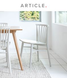 two white chairs sitting next to a wooden table on top of a carpeted floor