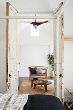 an open door leading to a bedroom with a bed and chair in the corner, next to a ceiling fan