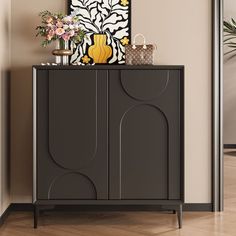 a black cabinet sitting in the corner of a room next to a vase with flowers