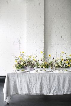 a table topped with two white plates covered in flowers next to a wall and window