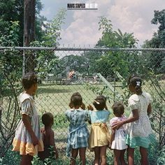 several children standing in front of a chain link fence