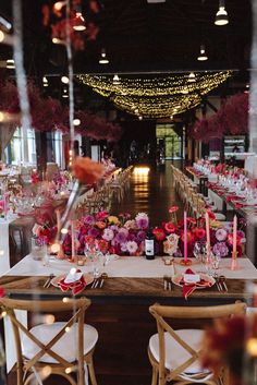 the tables are set with pink flowers and candles for an elegant wedding reception at night