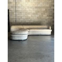 a white couch sitting in front of a brick wall with a lamp hanging from it's side