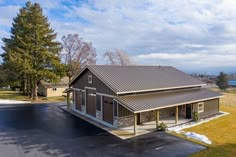 an empty parking lot in front of a building with a metal roof and two garages