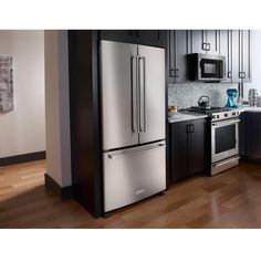 a kitchen with stainless steel appliances and black cabinets, including an oven, refrigerator, microwave, dishwasher and stove