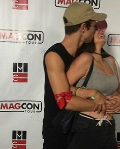 a man and woman kissing in front of a macon sign with the macon logo on it