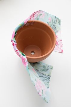 a brown bowl sitting on top of a white table next to a pink flowered napkin