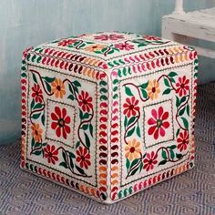 a brightly colored ottoman sitting on top of a blue floor next to a white bench