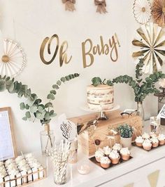 a baby shower table with cupcakes, cakes and other desserts on it