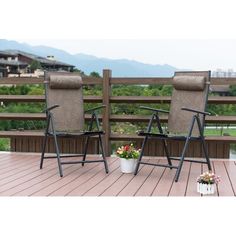 two lawn chairs sitting on top of a wooden deck next to a potted plant