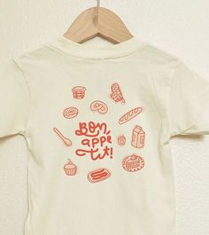 Handmade and designed kids' shirt with love by two mamas. Celebrate the joy of baking with our handmade kids' shirt, featuring a delightful bakery illustration! Adorned with a baguette, croissant, pretzel, doughnut, and adorable bakery accessories, plus a cute puffed bakery icon, this shirt adds a sprinkle of sweetness to any outfit. Perfect for little ones who love all things bakery! Bonus! get the Cute Bakery Sticker: a delightful peel-and-stick addition that transforms your picnic background Cute Organic Cotton T-shirt For Everyday, Bakery Accessories, Picnic Background, Bakery Illustration, Bakery Icon, Cute Bakery, Toddler Baby Boy, Heat Press Designs, Handmade Kids