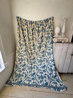 a blue and white blanket sitting on top of a wooden floor next to a window