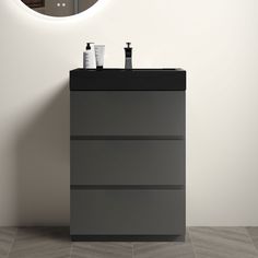 a bathroom vanity with two bottles on it and a round mirror above the sink, in front of a white wall