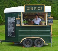 a man is behind the counter of a green food truck that has gin fizz written on it