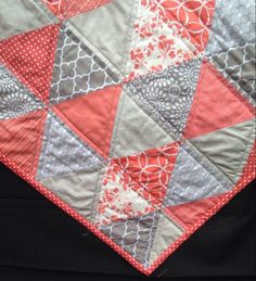 an orange and gray quilt on top of a black cloth