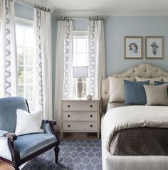 a bed room with a neatly made bed and two chairs next to each other in front of windows