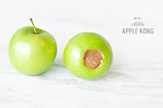 two green apples sitting on top of a white counter next to an apple with a bite taken out of it