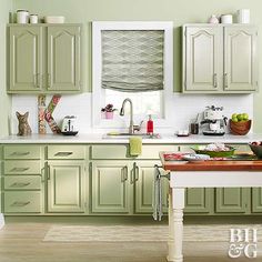 a kitchen with green cabinets and white counter tops