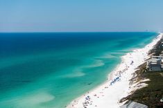 an aerial view of the beach and ocean in clear blue water, with white sand