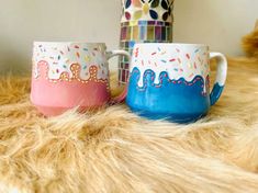 two colorful mugs sitting on top of a furry surface