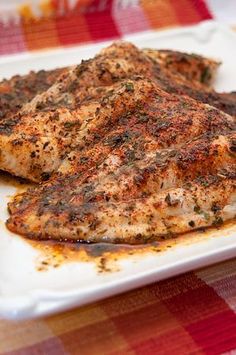 baked fish on a white plate sitting on a checkered tablecloth with text overlay