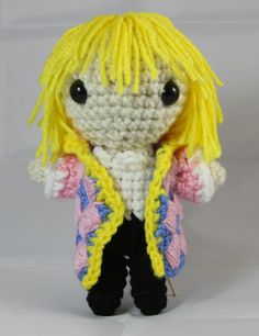 a crocheted doll with blonde hair and black pants, wearing a yellow jacket