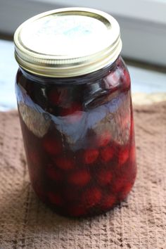 a glass jar filled with red liquid sitting on top of a brown cloth covered table