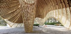 the inside of a bamboo structure with people sitting on benches under it and trees in the background