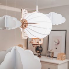 a white lamp hanging from the ceiling in a room with clouds and a clock on it