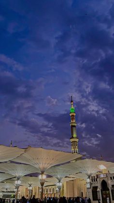 people are standing under umbrellas in the evening