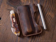 a pen and knife sitting on top of a brown leather case next to a lighter