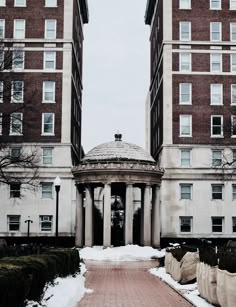 two tall buildings with pillars in front of them and snow on the ground around them