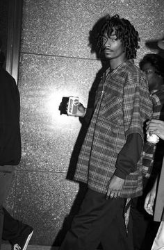 a man with curly hair is walking down the street while holding a coffee cup in his hand