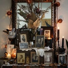 a table topped with pictures and candles next to a mirror