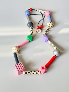 the necklace is made out of different colored beads and plastic objects on a white surface