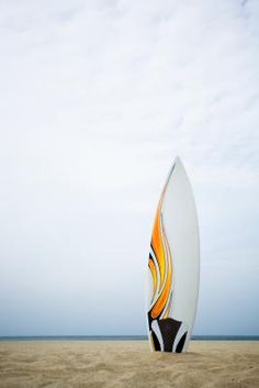 a white surfboard sitting on top of a sandy beach