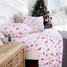 a christmas tree is in the corner of a bedroom with white and red bedding