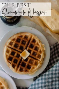 two waffles with butter on top sitting on a white plate next to some bread