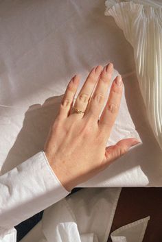 a woman's hand with a ring on top of some white sheets and pillows