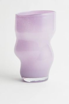 a purple glass cup sitting on top of a white table next to a black object