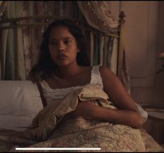 a woman sitting on top of a bed under a blanket