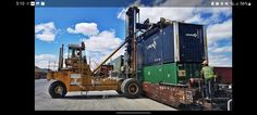 a man standing on top of a forklift in front of a cargo container truck