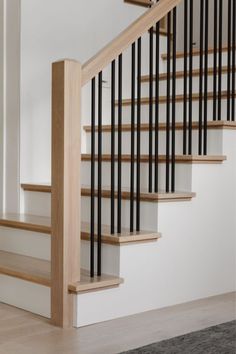 a staircase with black railing and wooden handrails in an empty room next to a carpeted floor