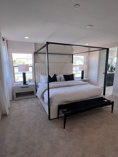 a large white bed sitting in a bedroom next to two lamps on either side of the bed